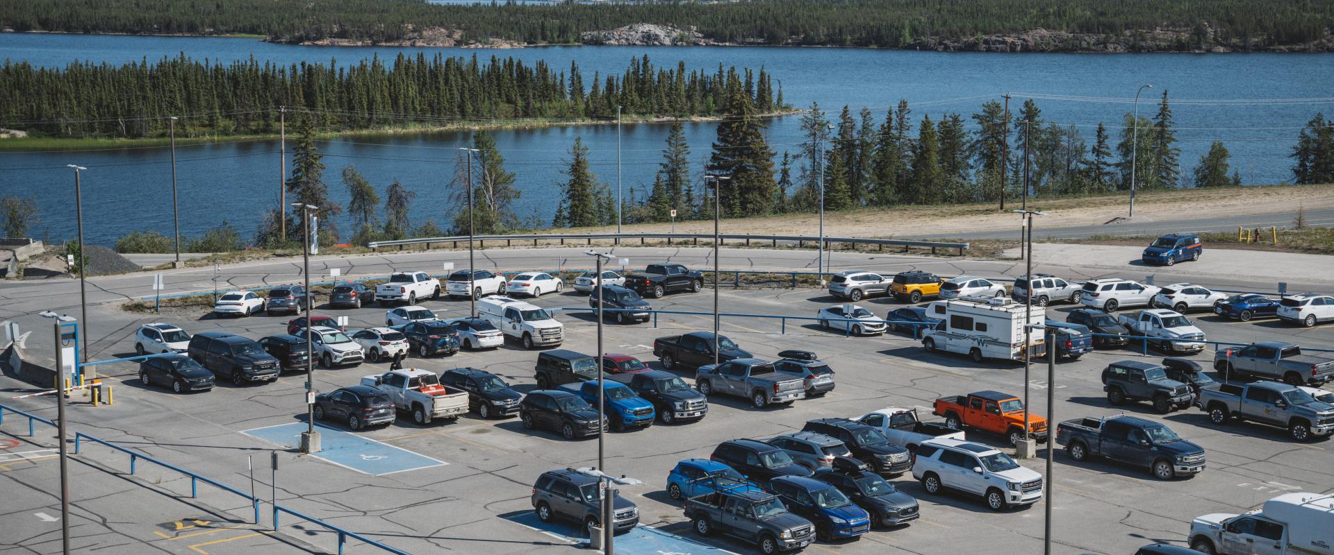 The image showcases a parking lot filled with numerous cars parked at Yellowknife Airport.