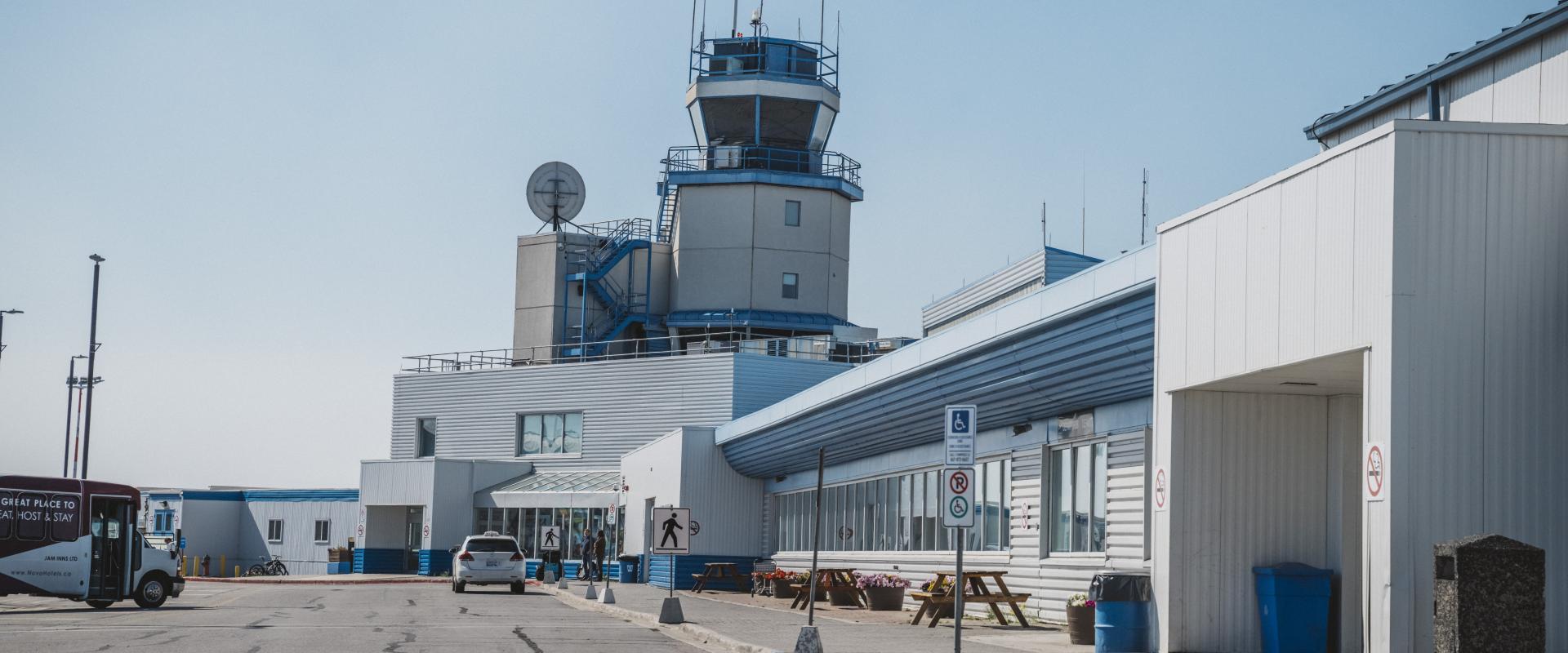 The image features an airport with a large air traffic control tower in the background.