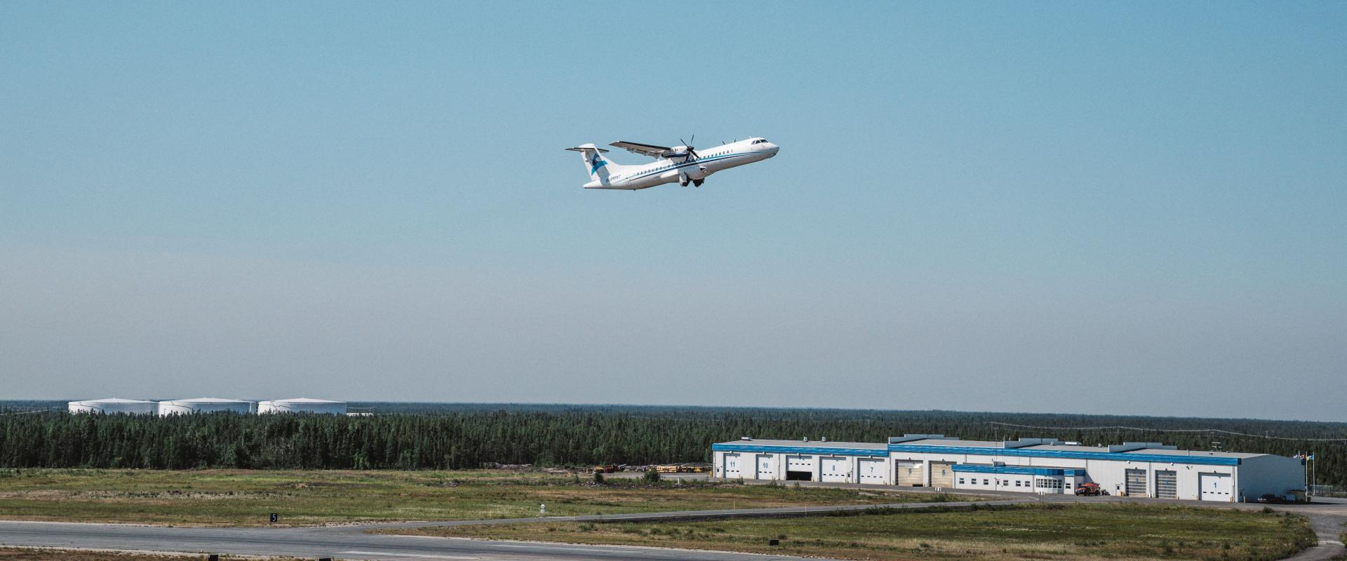 The image depicts an aircraft taking off from Yellowknife airport